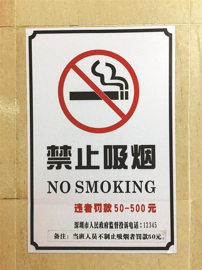 一位旅客蹲着吸烟,其左手边张贴有"禁止吸烟"告示牌