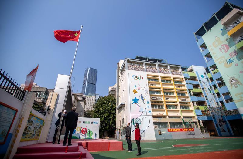 红桂小学校长叶育枢与学内3名教师一同在操场上升国旗.