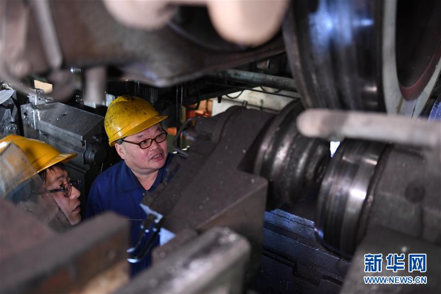 2月21日,机车镟轮工张杰(右)和工友朱永强在西安机务段检修车间讨论