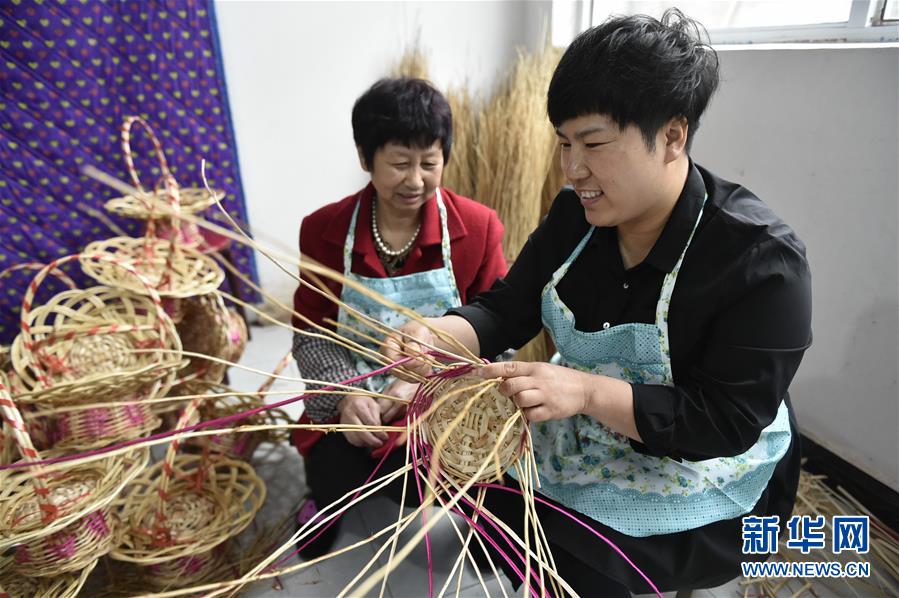 4月24日,在固安县大孙郭村的柳编工厂,刁新影(右)指导工人制作柳编